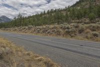 a lonely road in front of mountains and trees with no one riding it's bicycle