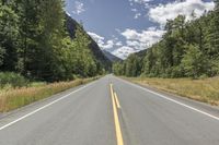 a very wide open highway with some pine trees by the side of the road,