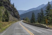 a mountain road is between two large mountains and the bottom of a steep cliff is visible