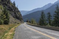 a mountain road is between two large mountains and the bottom of a steep cliff is visible