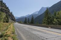 a mountain road is between two large mountains and the bottom of a steep cliff is visible