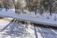 a snowy road with a sign on the roadside side is shown from above the tree line