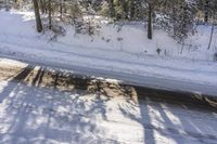 a snowy road with a sign on the roadside side is shown from above the tree line