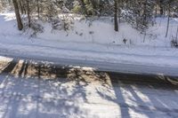 a snowy road with a sign on the roadside side is shown from above the tree line