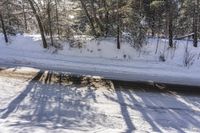 a snowy road with a sign on the roadside side is shown from above the tree line