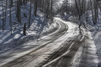 the road is covered with fresh snow as it's about to pass through the woods