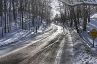 the road is covered with fresh snow as it's about to pass through the woods