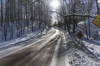 the road is covered with fresh snow as it's about to pass through the woods