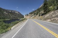 a mountain pass with road alongside the river in a valley with tall trees on either side of the road