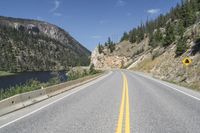 a mountain pass with road alongside the river in a valley with tall trees on either side of the road