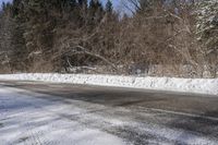 the snowy road is lined with snow and trees on both sides of it and no cars or people crossing