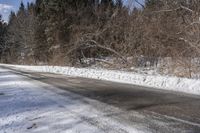 the snowy road is lined with snow and trees on both sides of it and no cars or people crossing