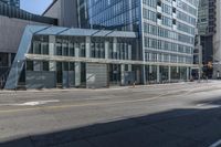 a street with many people walking and walking in front of a building with glass walls