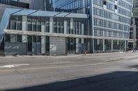 a street with many people walking and walking in front of a building with glass walls