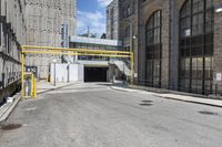 a view down an empty city street at the entrance to the industrial building with a ramp for people