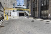 a view down an empty city street at the entrance to the industrial building with a ramp for people