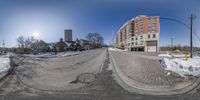 a circular photograph of a street with snow on ground and a building behind it in winter