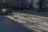 an empty city street in front of tall buildings with parked cars on it's side