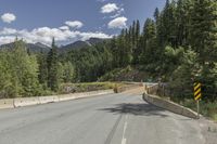 a red triangle is in the middle of the road near the tree line and mountains