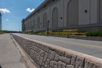 an empty city street is blocked off by a bridge and grass and shrubs are in front of it