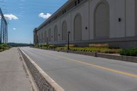 an empty city street is blocked off by a bridge and grass and shrubs are in front of it