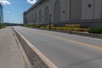 an empty city street is blocked off by a bridge and grass and shrubs are in front of it