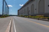 an empty city street is blocked off by a bridge and grass and shrubs are in front of it