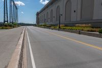 an empty city street is blocked off by a bridge and grass and shrubs are in front of it