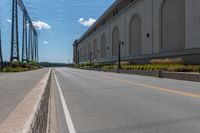 an empty city street is blocked off by a bridge and grass and shrubs are in front of it