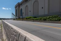 an empty city street is blocked off by a bridge and grass and shrubs are in front of it