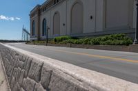 an empty city street is blocked off by a bridge and grass and shrubs are in front of it