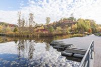 a dock sitting on the side of a lake surrounded by fall trees and a path