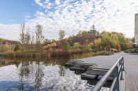 a dock sitting on the side of a lake surrounded by fall trees and a path