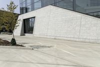 a skateboarder performs a stunt on a cement path next to some trees and bushes