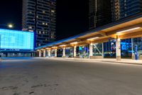 a building sitting beside the curb of a street at night, with traffic coming in