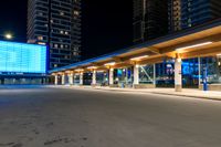 a building sitting beside the curb of a street at night, with traffic coming in