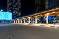 a building sitting beside the curb of a street at night, with traffic coming in