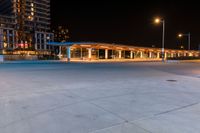 the outside view of a parking garage at night time and illuminated in street lamps and other buildings