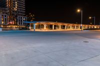 the outside view of a parking garage at night time and illuminated in street lamps and other buildings