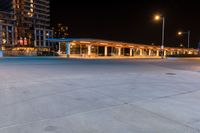 the outside view of a parking garage at night time and illuminated in street lamps and other buildings