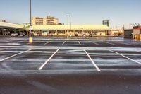 a parking lot filled with lots of white lines and a building in the background from a very cold day