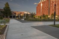 a city street surrounded by grass and tall buildings at the end of a street there is a paved pathway in front of the building