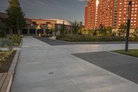 a city street surrounded by grass and tall buildings at the end of a street there is a paved pathway in front of the building