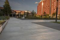 a city street surrounded by grass and tall buildings at the end of a street there is a paved pathway in front of the building