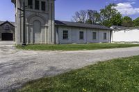 an empty road leading through a building and grassy area with a gate and a clock tower