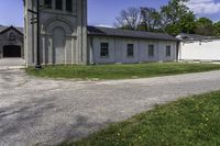 an empty road leading through a building and grassy area with a gate and a clock tower