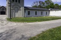 an empty road leading through a building and grassy area with a gate and a clock tower