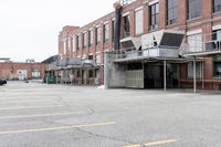 the empty parking lot has only snow on the ground in front of an old brick factory