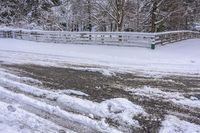 a bunch of snow is piled onto the road in front of a wooden bridge near a forest