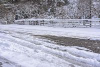 a bunch of snow is piled onto the road in front of a wooden bridge near a forest